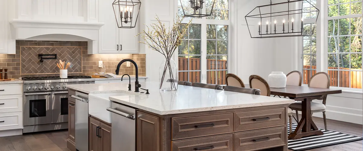 Bright kitchen remodeling in Alpharetta with a large island, white cabinets, stainless steel appliances, and modern pendant lighting above the dining area