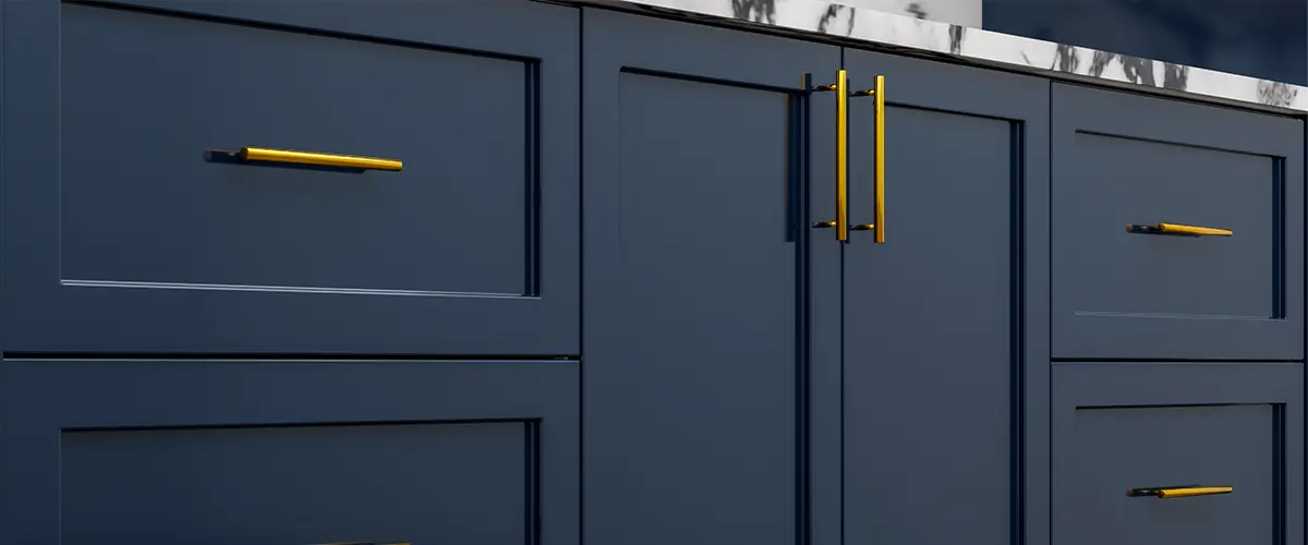 Close-up of navy blue kitchen cabinets with gold handles and marble countertop. Cabinet Vs Cupboard