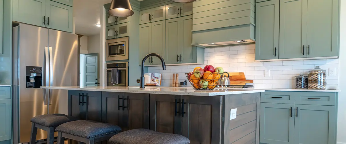 Contemporary kitchen with mint green cabinets, stainless steel appliances, and a wood island.