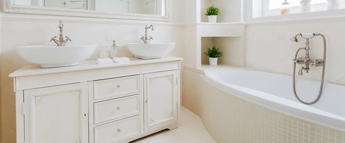 Luxurious white bathroom with vessel sinks, large mirror, and soaking tub, featuring classic design elements.