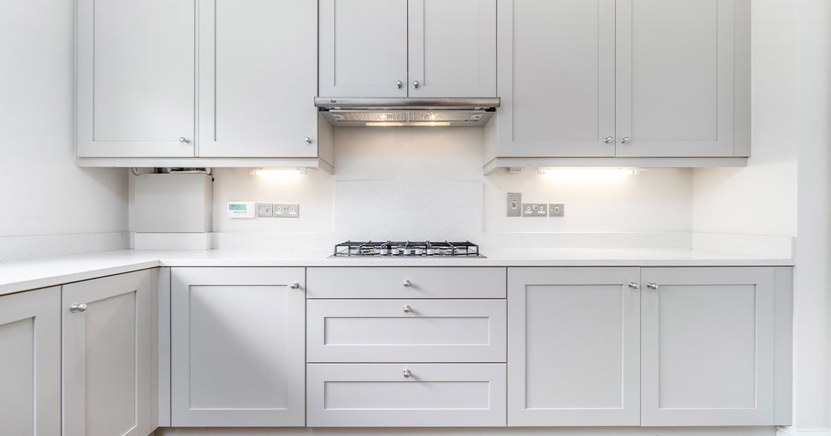 Modern kitchen with sleek grey cabinets, white countertops, and under-cabinet lighting.