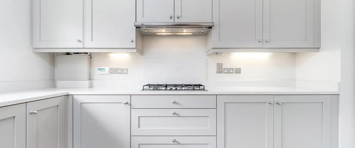 Modern kitchen with sleek grey cabinets, white countertops, and under-cabinet lighting.