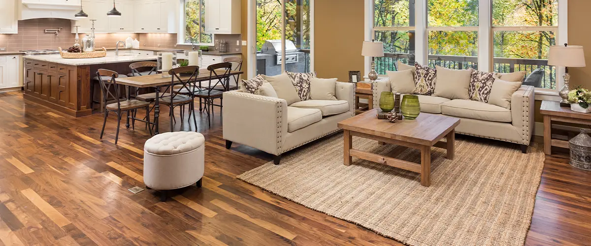 Open-concept living room and kitchen featuring rich walnut hardwood flooring and cozy, neutral furnishings.