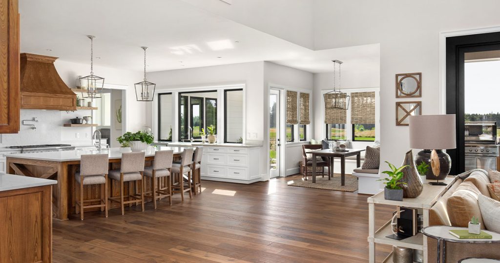 Luxury open-concept kitchen and dining area with hardwood flooring, modern lighting, and farmhouse-style décor.