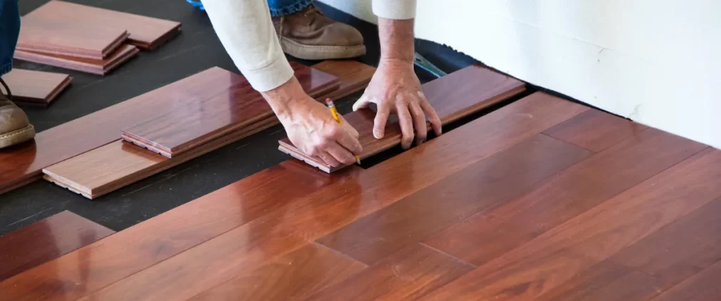 Worker installing hardwood flooring by fitting planks together.