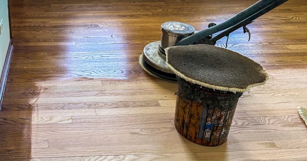 Close-up of a floor buffing machine polishing a wooden floor for a glossy finish.