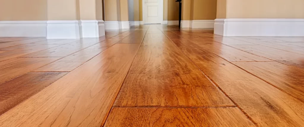 Close-up of polished hardwood flooring with a glossy finish in a bright home interior.